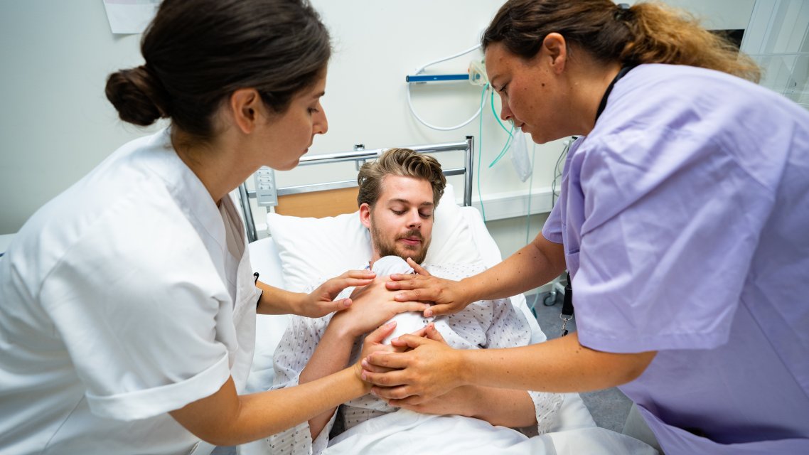 Sykepleiere hjelper far med nyfødt på brystet