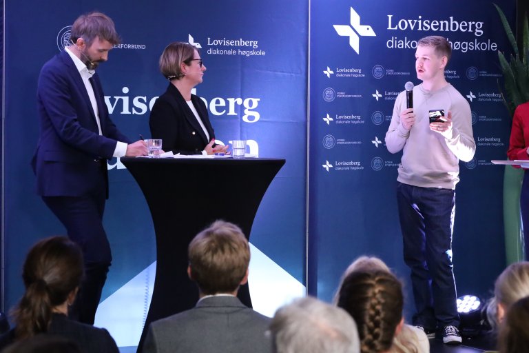 Sykepleierstudent Jonathan Øverland-Heidegård stiller politikerne spørsmål på scenen.