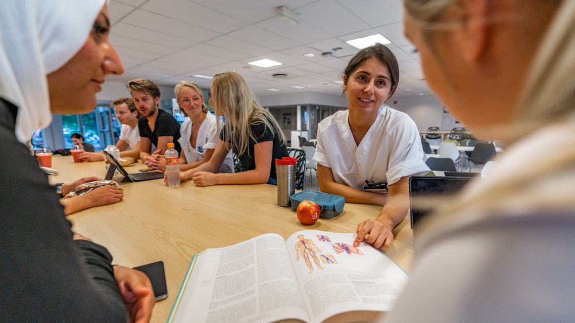 Studenter i kantina som diskuterer pensum