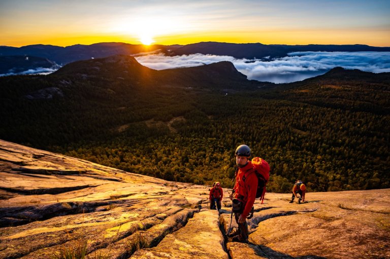 Studenter klatrer i fjellet i solnedgang