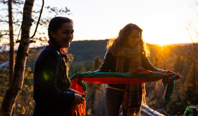To studenter pakker opp hengekøye i solnedgang